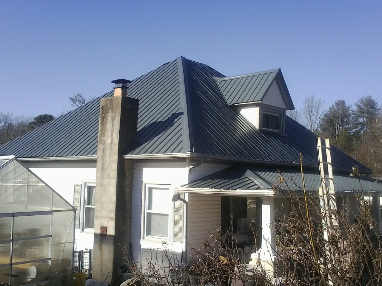 Dark blue standing seam metal roof on a white farmhouse with dormer — Slate & Tile Roof Repair by Roofing Brothers in Pikesville