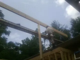 Carpenter setting a ridge beam over a new addition frame — Ice Dam Removal by Roofing Brothers in Pikesville