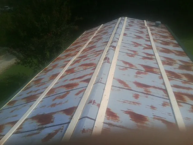 Rusted metal roof panels with new wood purlins before replacement — Storm Damage Roof Repair in Pikesville by Roofing Brothers