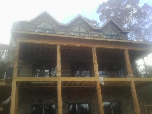Dormers and porch framing on a large log home under construction — Roof Coating work by our crew in Pikesville