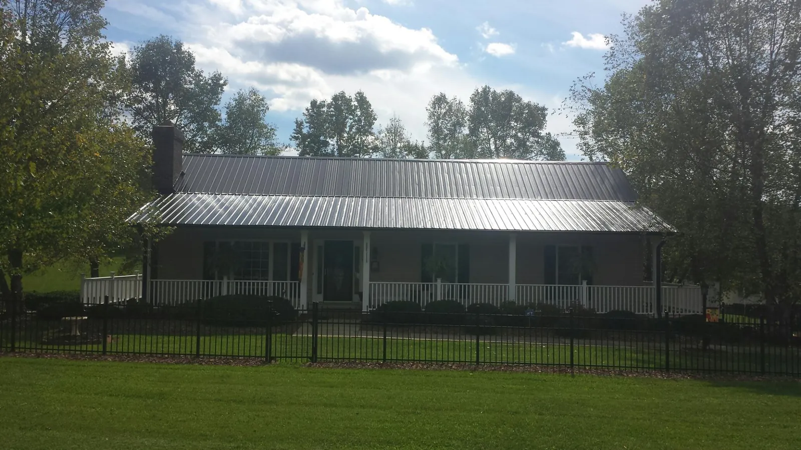 Gray metal roof on a brick ranch with a full width front porch — Gutter Guard Installation work by our crew in Pikesville