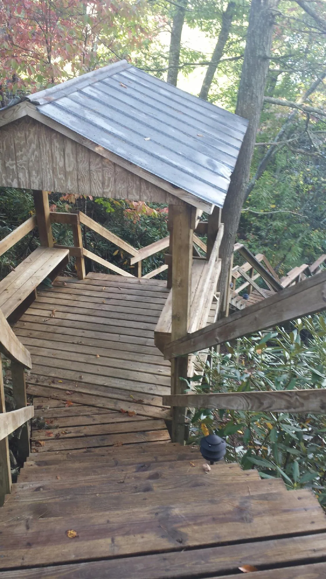 Metal roofed shelter over wooden steps on a wooded walkway — Skylight Repair & Installation work by our crew in Pikesville