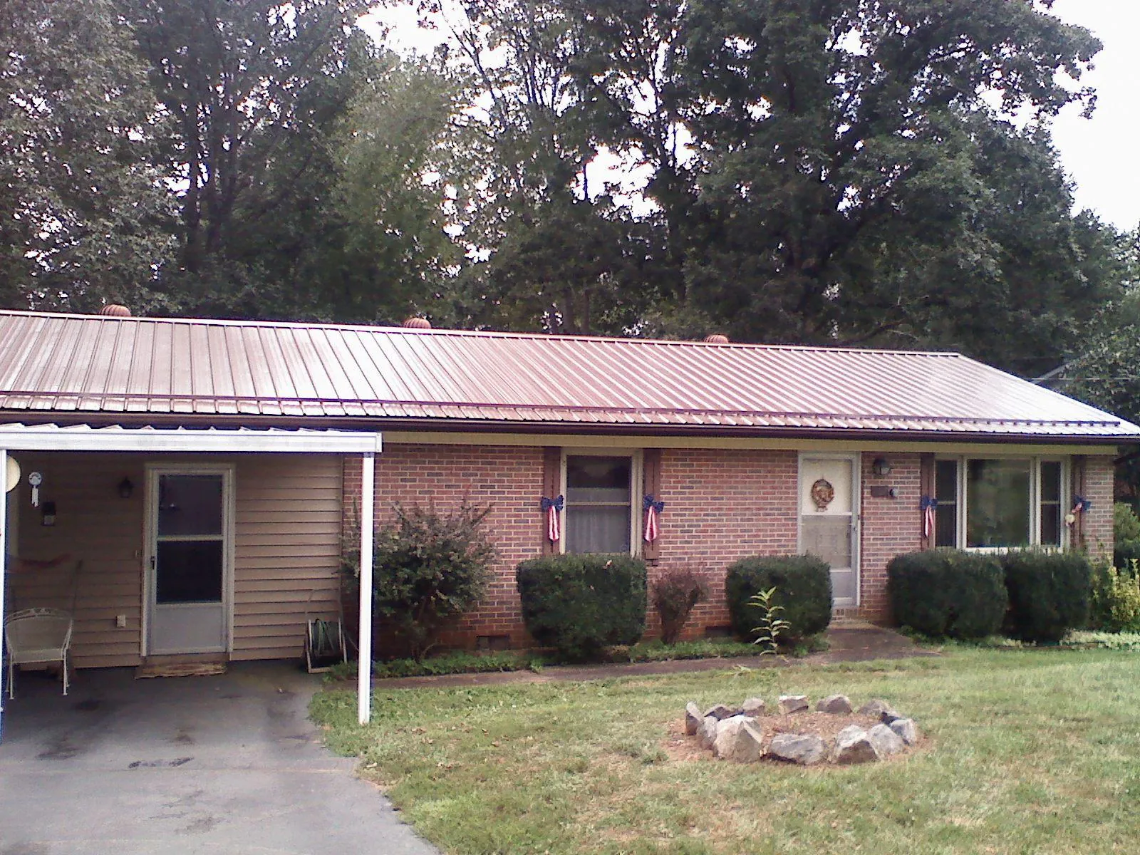 Bronze metal roof and carport on a brick ranch home — Roof Repair work by our crew in Pikesville