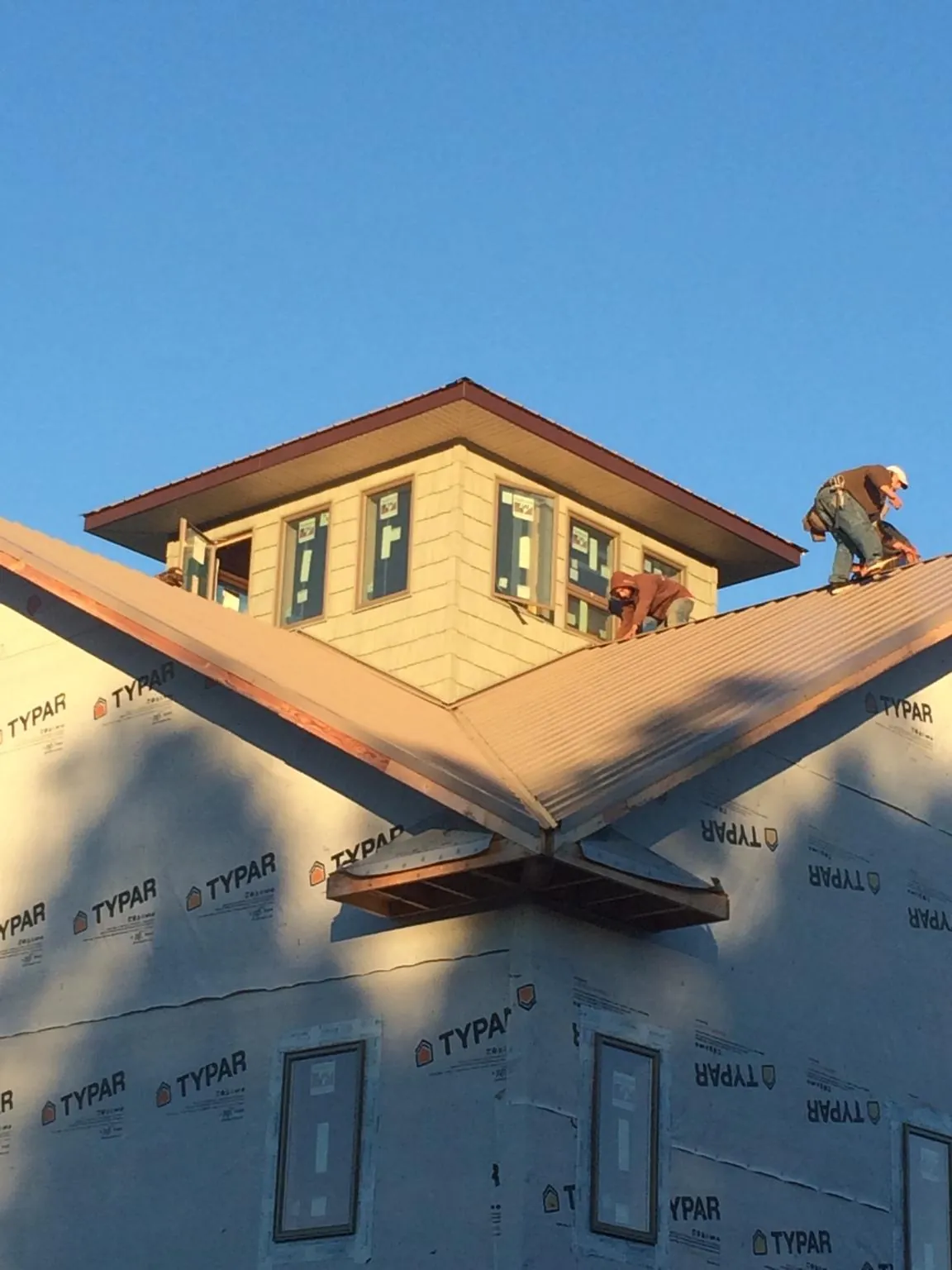 Roofers working around a rooftop cupola on a new metal roof at sunset — Roof Waterproofing in Pikesville by Roofing Brothers